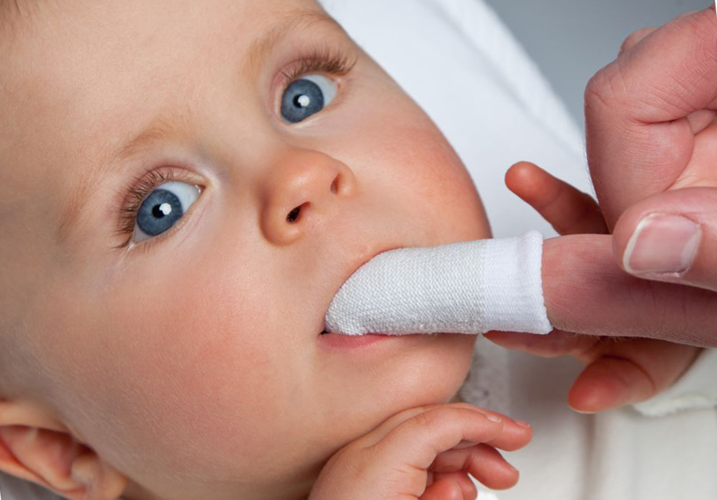 На фото показана гигиена полости рта у младенца с помощью специальной салфетки