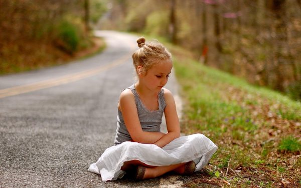 Девочка сидит на дороге