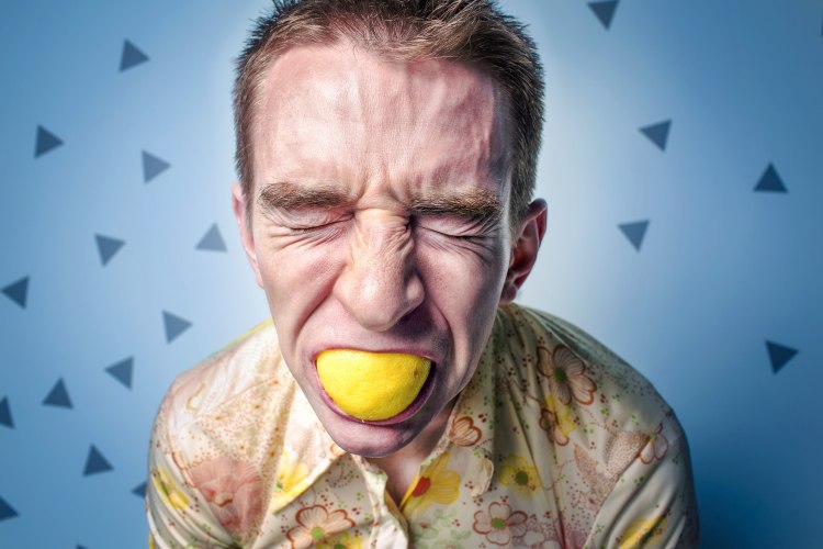Man in stress with lemon in his mouth